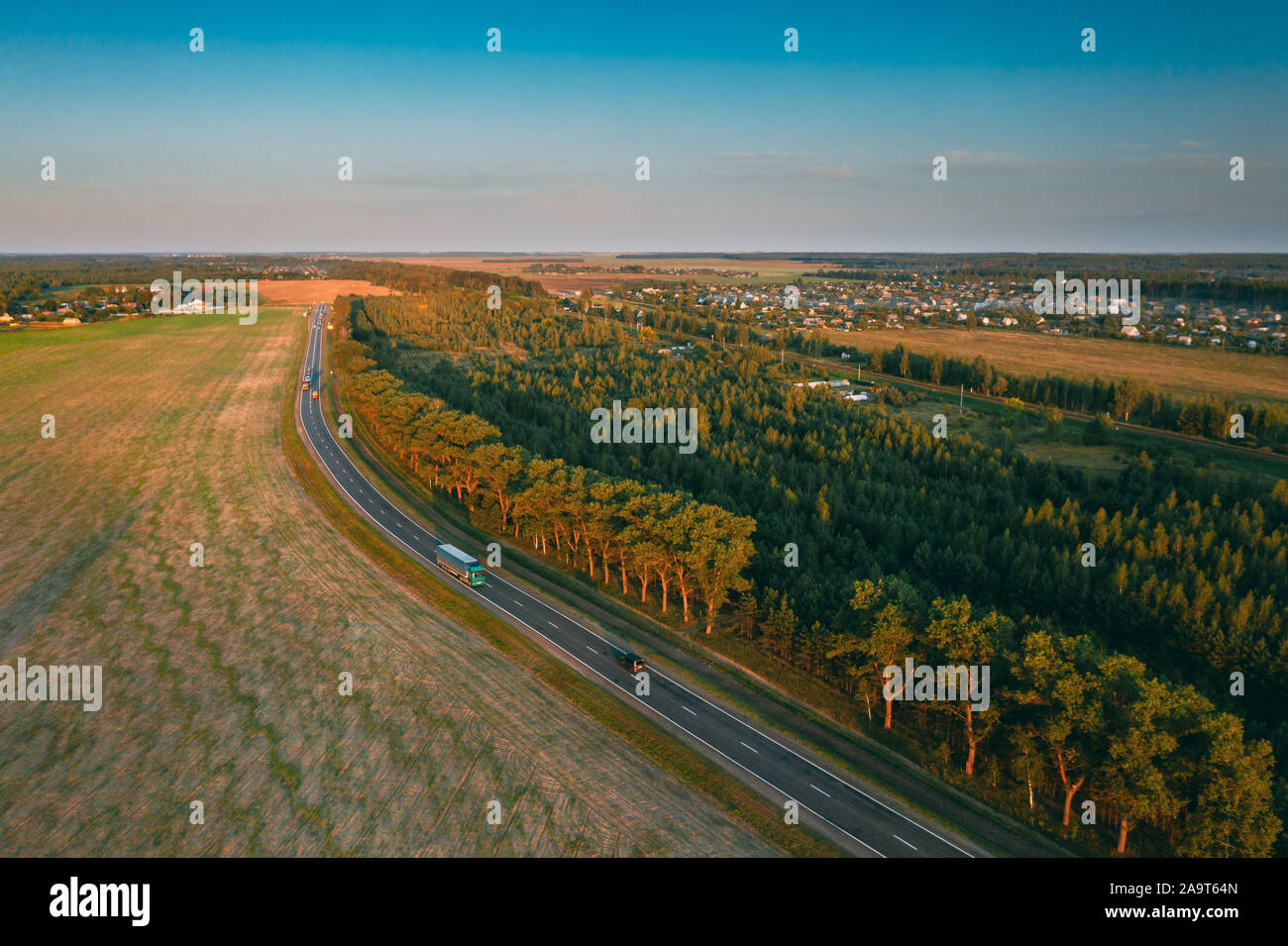 Luftaufnahme von Autobahn Straße durch das Feld und im Sommer grüne Wald Landschaft. Blick von oben auf die Lkw Zugmaschine mit Ballastpritsche Triebfahrzeug In Motion auf Fre Stockfoto