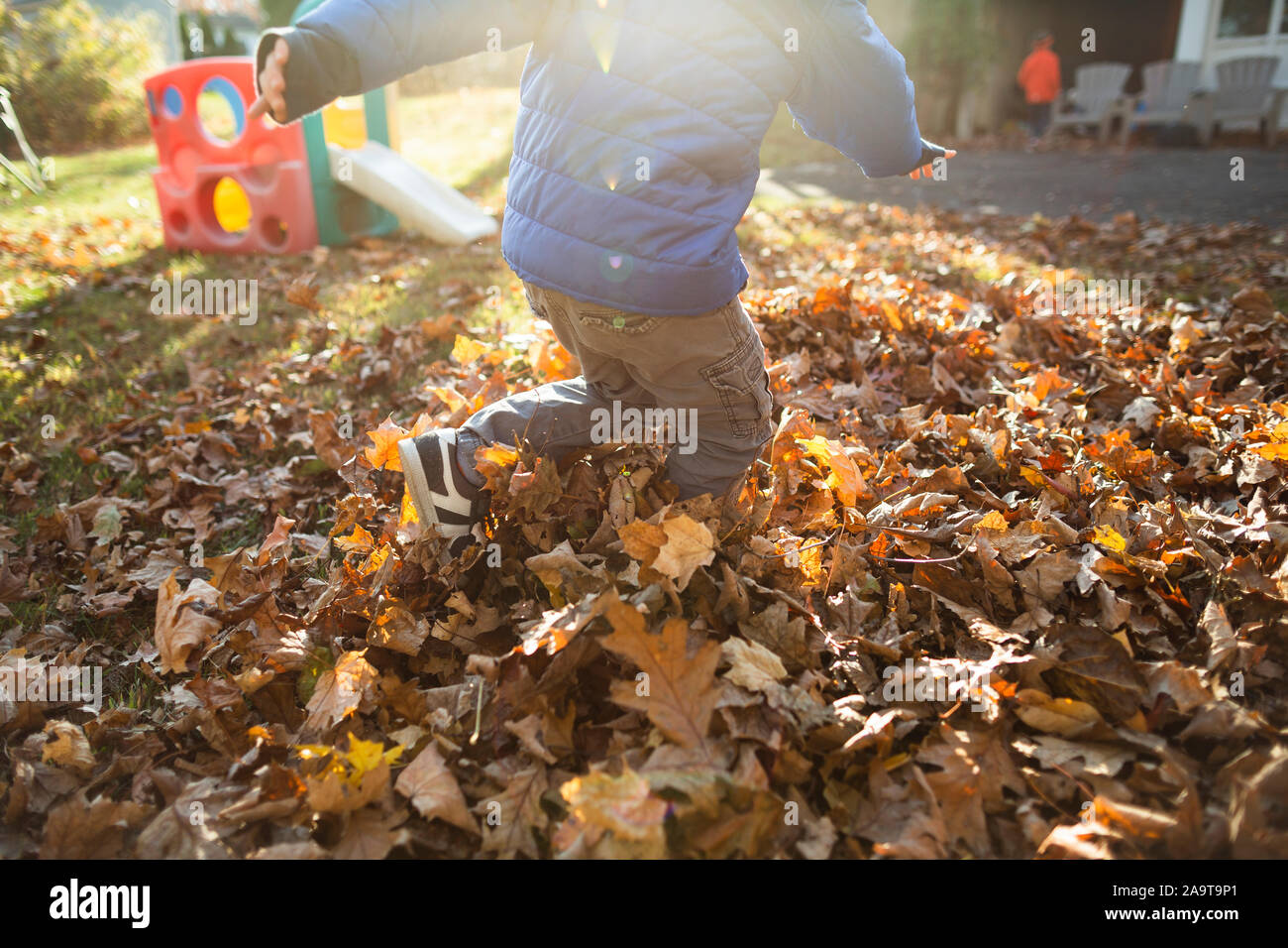 Körper des Kindes spielen im Freien in einem Haufen Laub im Herbst Stockfoto