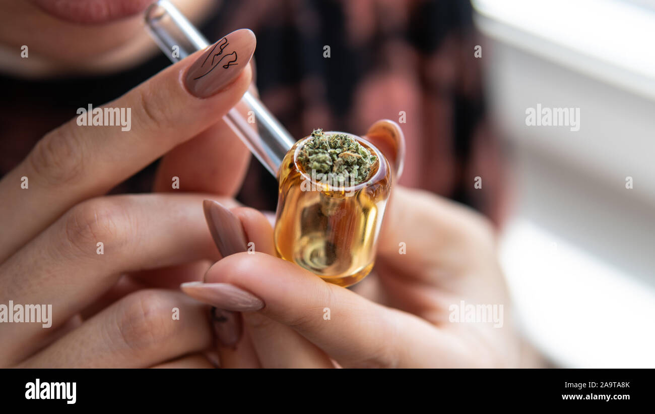 Europäische Mädchen Marihuana raucht, durch ein Glasrohr. Rauchen von Cannabis durch das Glas Rohr Stockfoto