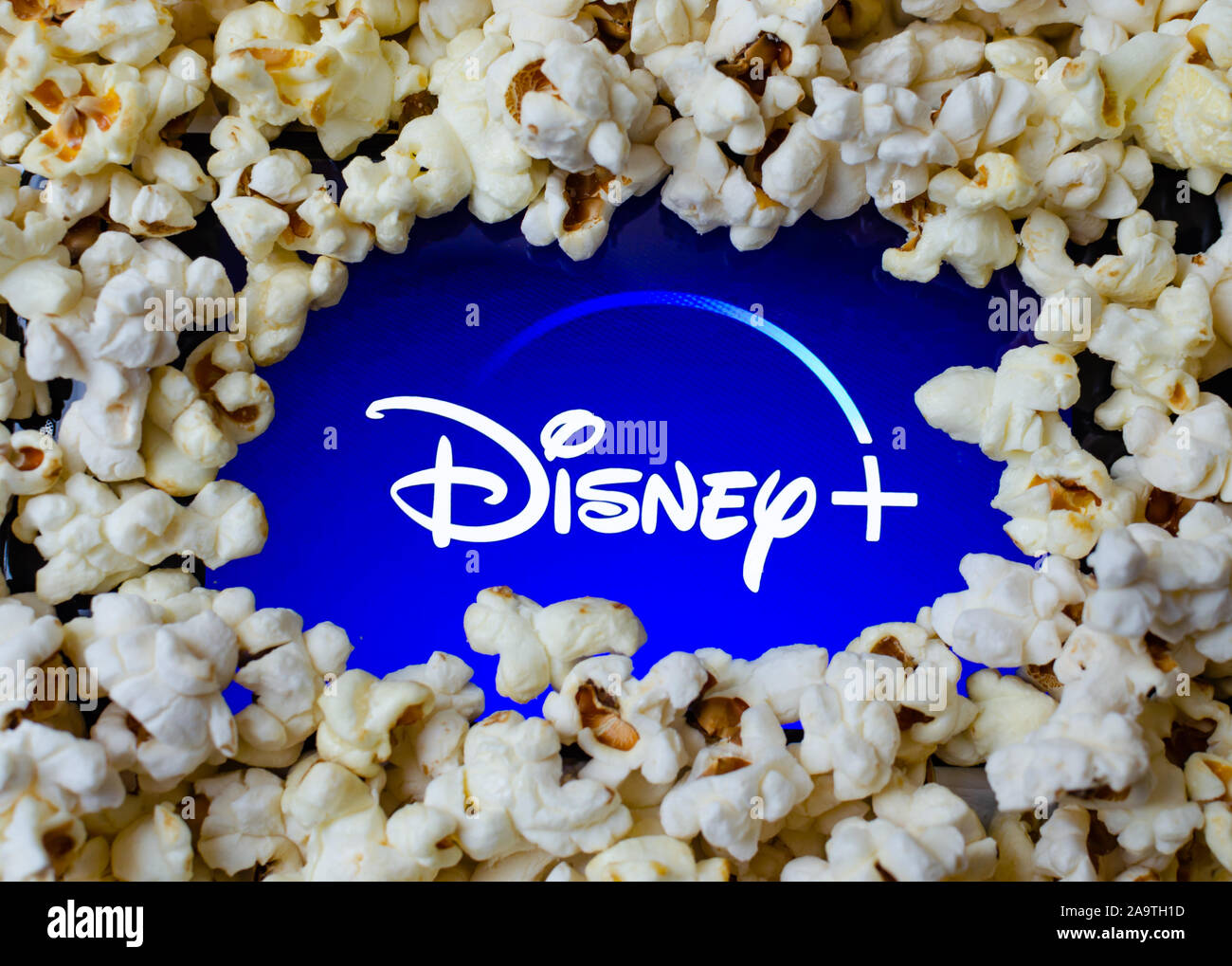 Disney + Logo auf einem Bildschirm mit Popcorn abgedeckt. Konzept Foto für Home Entertainment und neue Video Streaming Service. Stockfoto