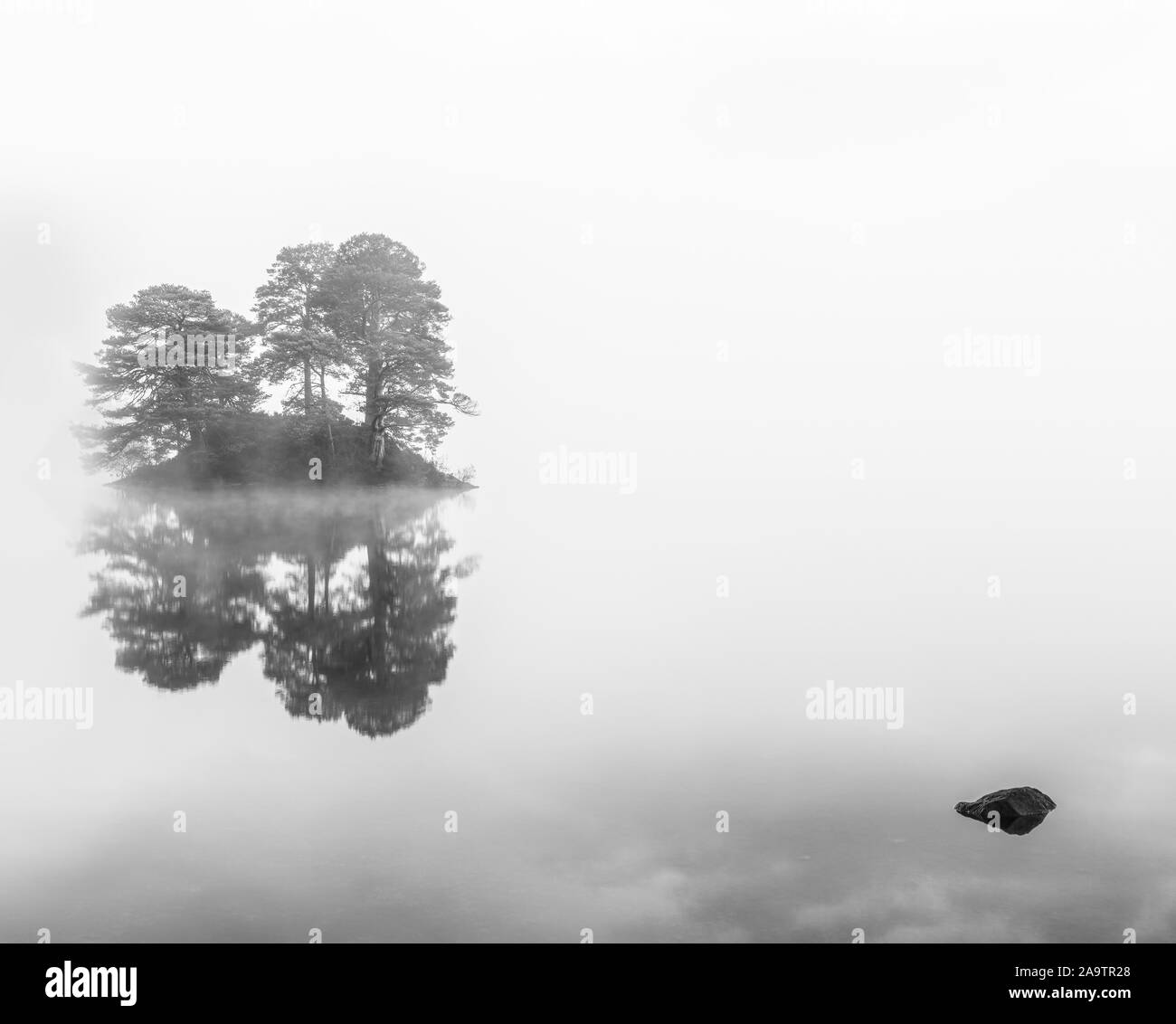 Isolierte Insel Reflexionen im Herbst Nebel Stockfoto