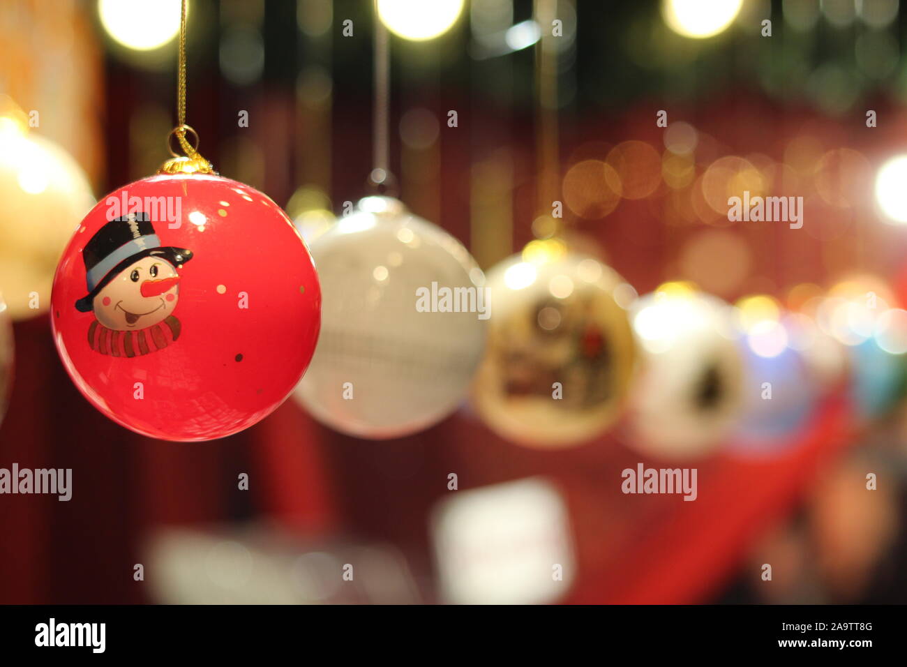 Rote Weihnachtskugel mit Schneemann und Zeile des unscharfen Flitter und Bokeh Festliche Lichter Stockfoto