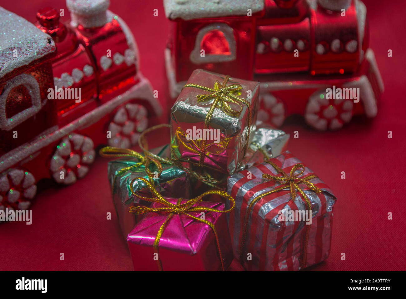 Rote Zugornamente mit Weihnachtsgeschenken auf rotem Hintergrund, Foto-Illustration Stockfoto