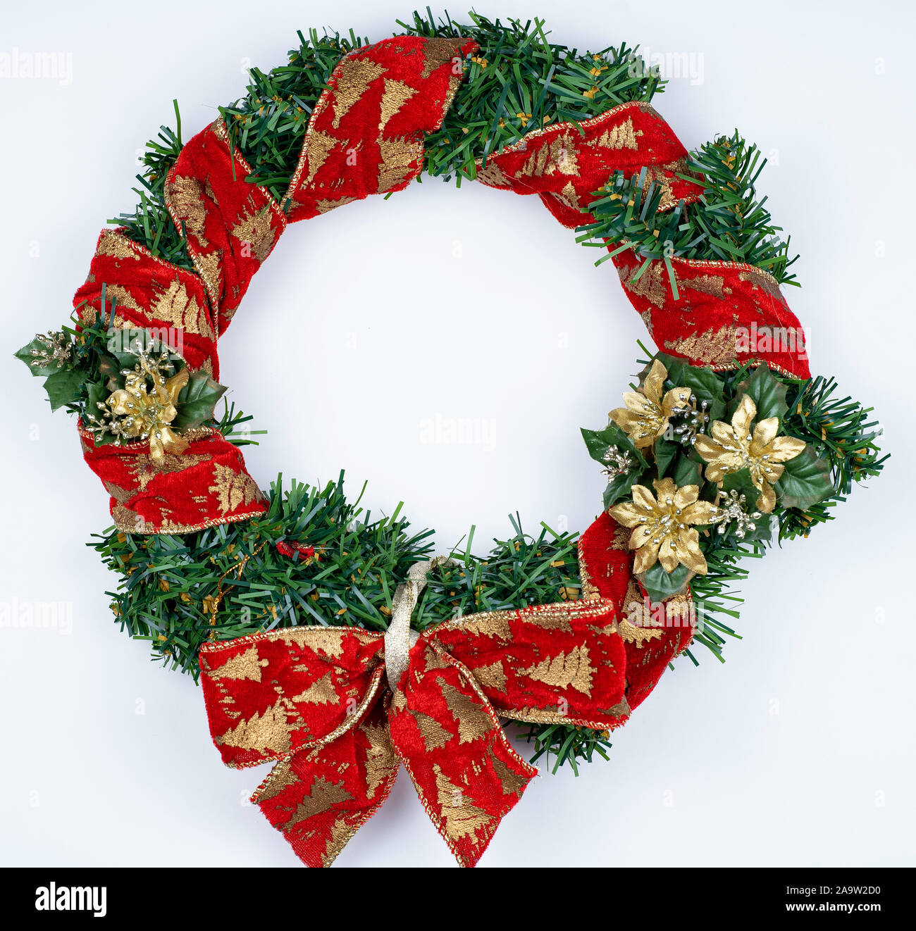 Weihnachten Kranz auf weißem Hintergrund. Red Ribbon auf grünem künstlichen Kiefer und roten Bogen, goldene Blumen. Stockfoto