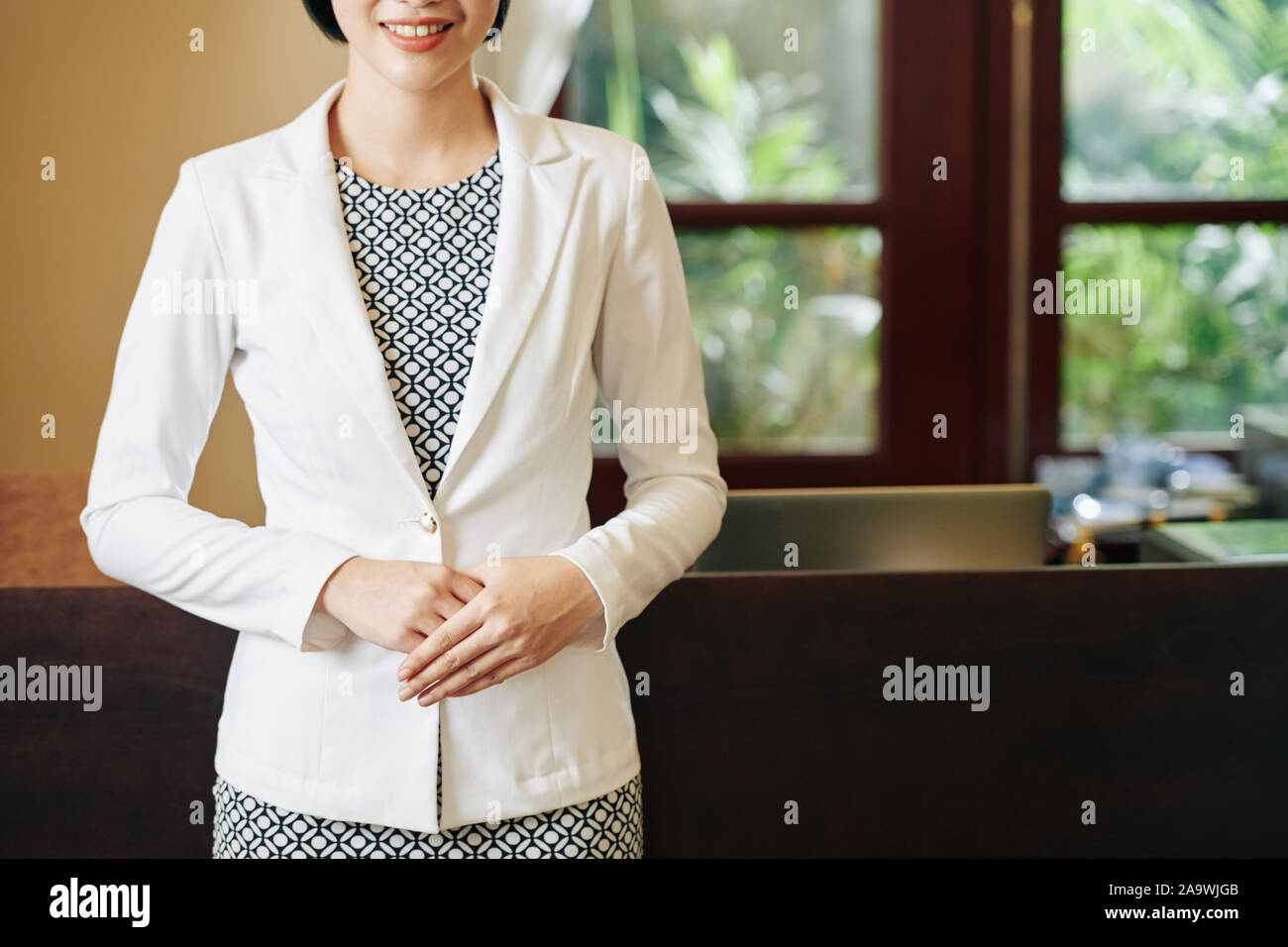 Zugeschnittenes Bild von lächelnden Dame in gepflegter Kleidung, die Sie Grußansage in Spa Salon oder Boutique Hotel Stockfoto
