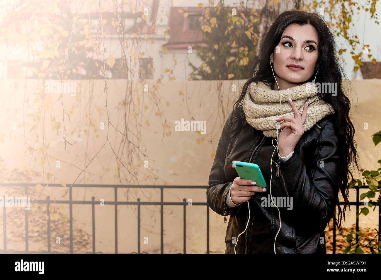 Porträt einer schöne Brünette Mädchen, auf orangem Hintergrund in einem Fahrrad und Jeans, die Musik hört Stockfoto