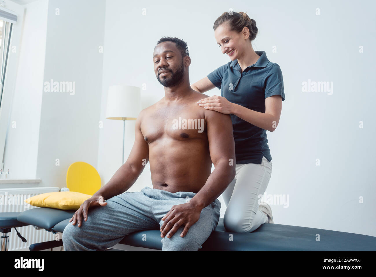 Physiotherapeuten massieren eine junge schwarze Mann auf die Schulter Stockfoto