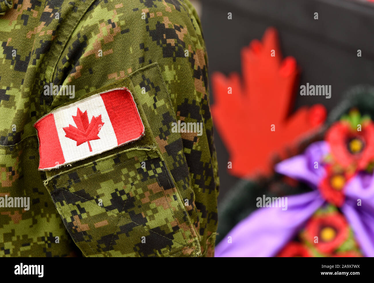 Canada Day. Flagge von Kanada auf der Uniform und Red Maple Leaf auf dem Hintergrund. Kanadische Soldaten. Armee von Kanada. Kanada Blatt. Erinnerung D Stockfoto