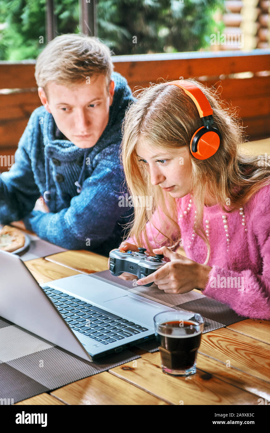 Girl Gamer in einem Cafe mit einem jungen Kerl. Mann essen Pizza Stockfoto