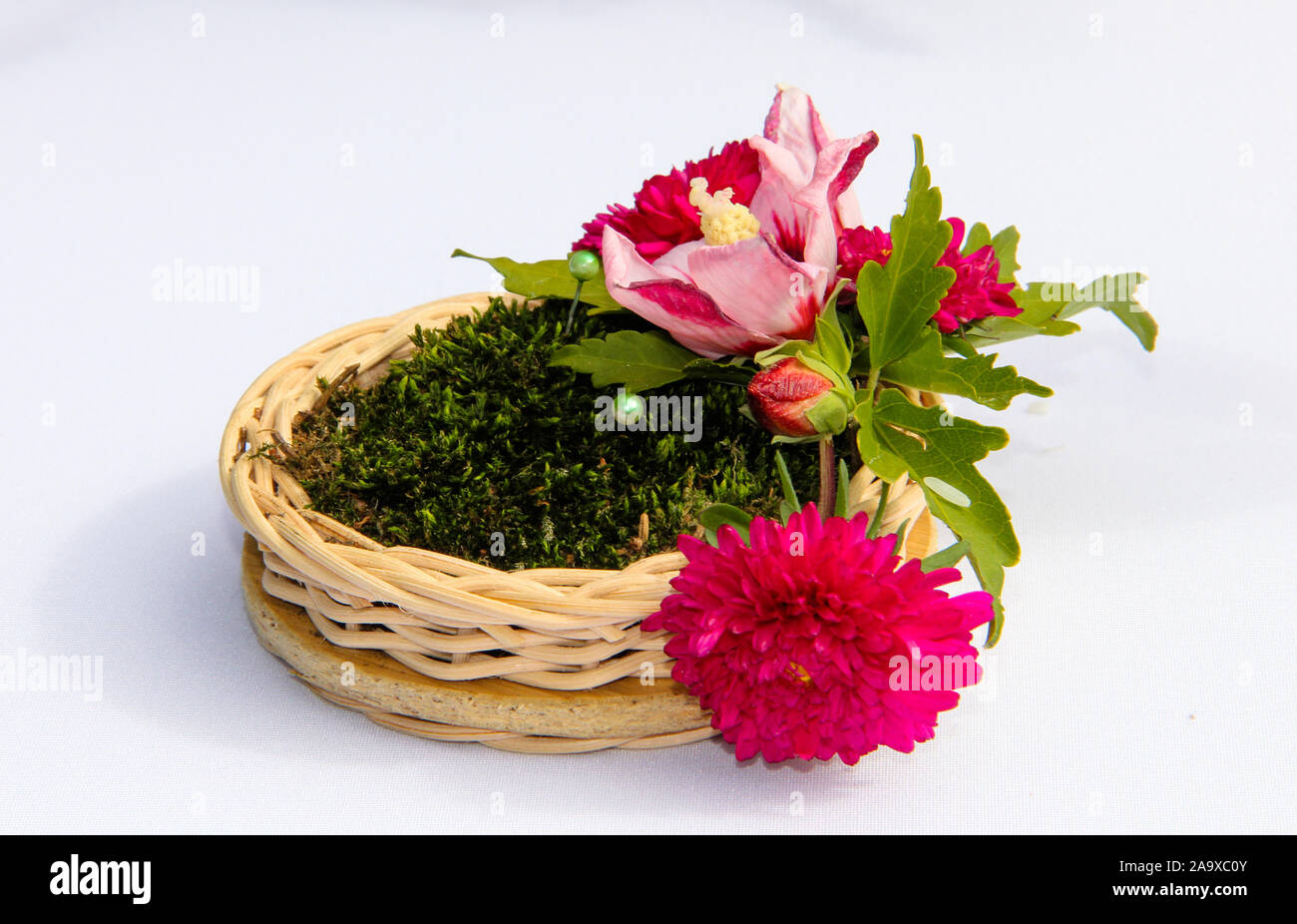Pad unter Trauringe im rustikalen Stil: Kleine Korb mit Moos und Blumen Stockfoto