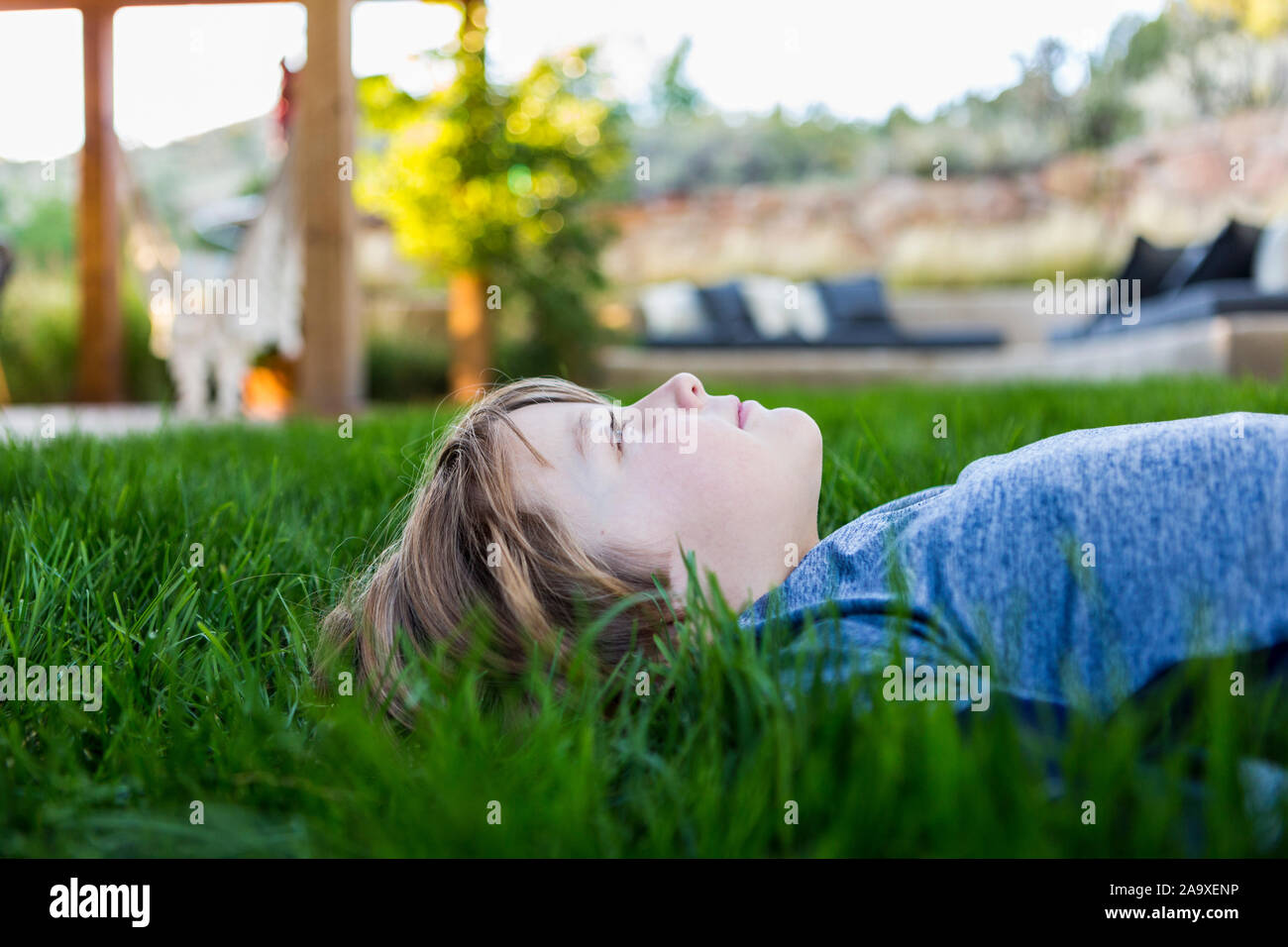 Portrait von LÄCHELNDEN 6-jährigen Jungen, der sich im grünen Gras Stockfoto