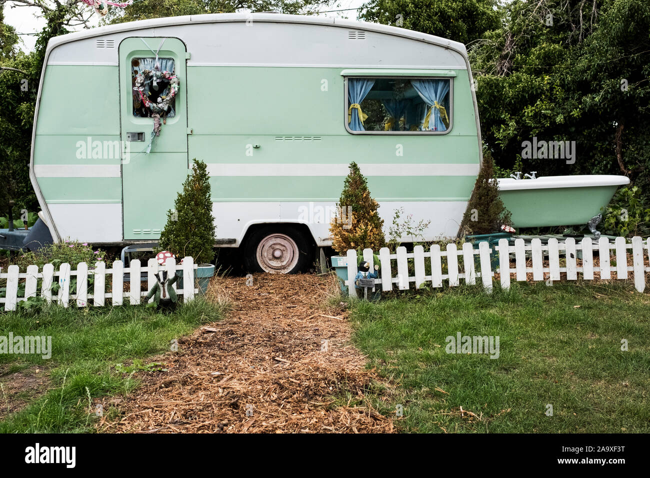 Weiß und Grün retro Caravan am Ende eines Garten Weg hinter niedrigen weißen Lattenzaun geparkt. Stockfoto