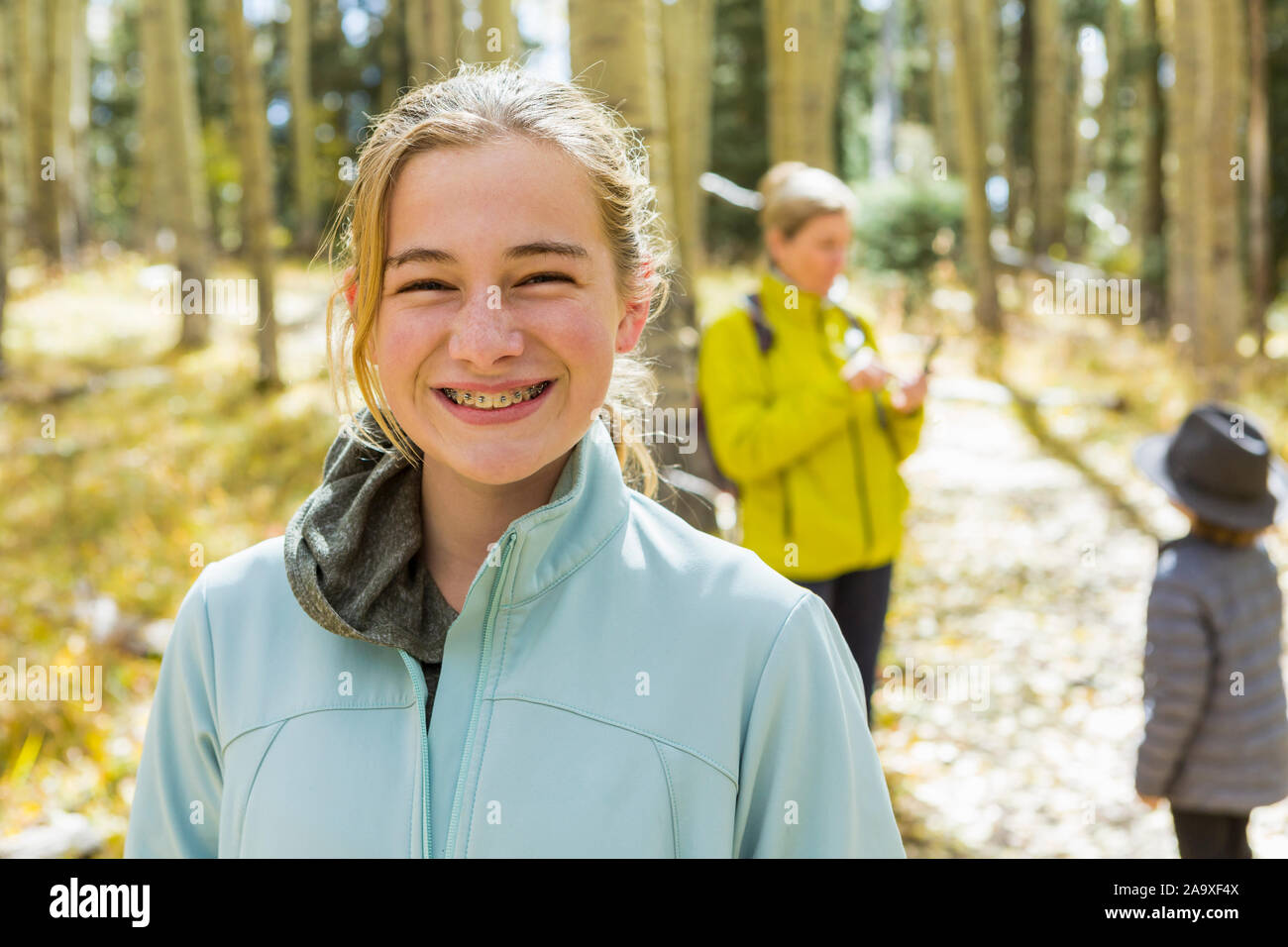 Eine reife Frau, Junge und Mädchen, eine Mutter und ihre zwei Kinder in Wäldern, Aspen Bäume im Herbst Farbe, Stockfoto