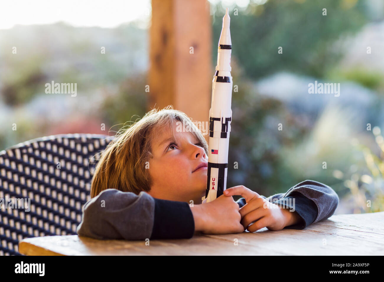 Ein Junge spielt mit einem Spielzeug Nasa Saturn 5 Rakete, Tag träumen über Raumfahrt. Stockfoto