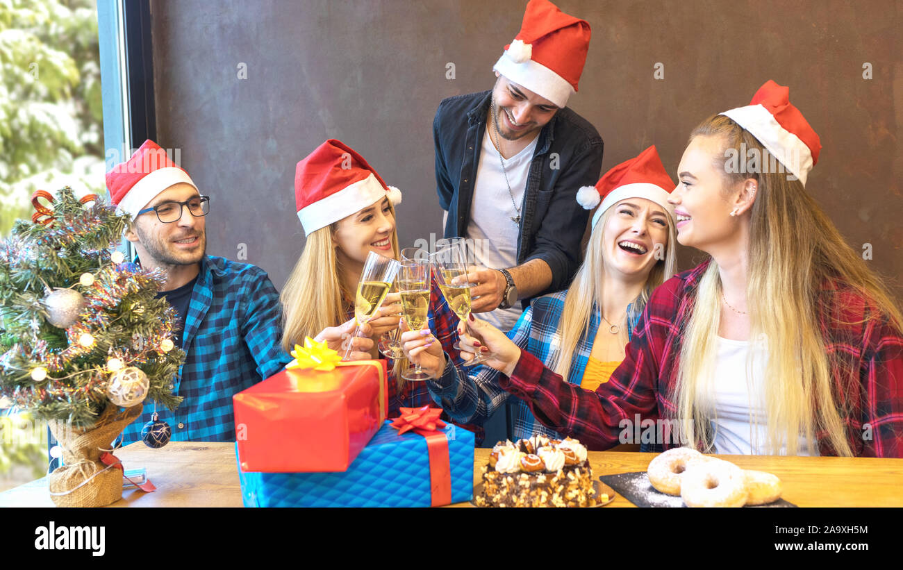 Glückliche junge Freunde mit Nikolausmützen feiern Weihnachten Champagner bei Party toasten. Stockfoto