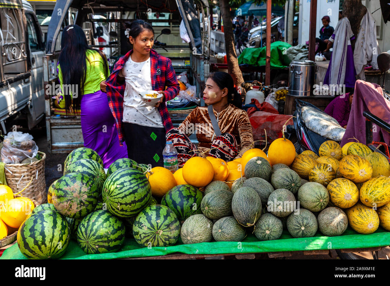 Die jungen burmesischen Frauen verkaufen Melonen zu einem Straßenmarkt, Mandalay, Myanmar. Stockfoto