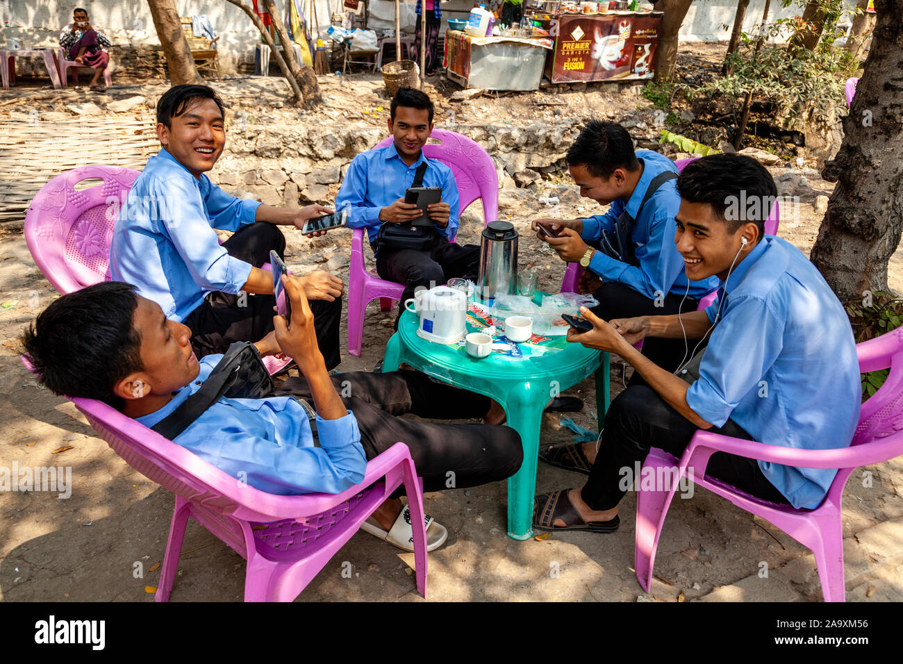 Eine Gruppe von Jungen burmesischen Männer sitzen um einen Tisch auf ihre Handys, Mandalay, Myanmar suchen. Stockfoto