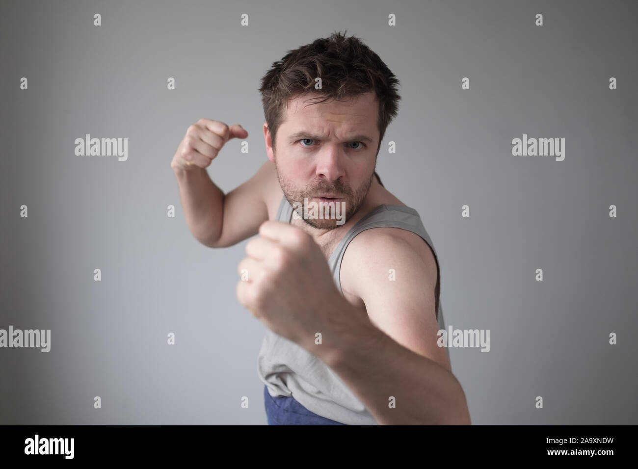 Häusliche Gewalt Konzept. Aggressive Mann mit erhobener Faust, als ob versucht, jemanden zu bedrohen, Schwere und ängstlichen Ausdruck. Studio sho Stockfoto