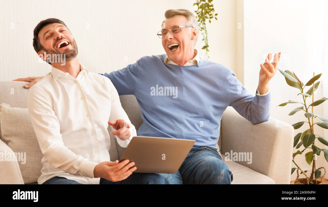 Middle-Aged Mann und Ältere Vater mit Laptop sitzen innen, Panorama Stockfoto