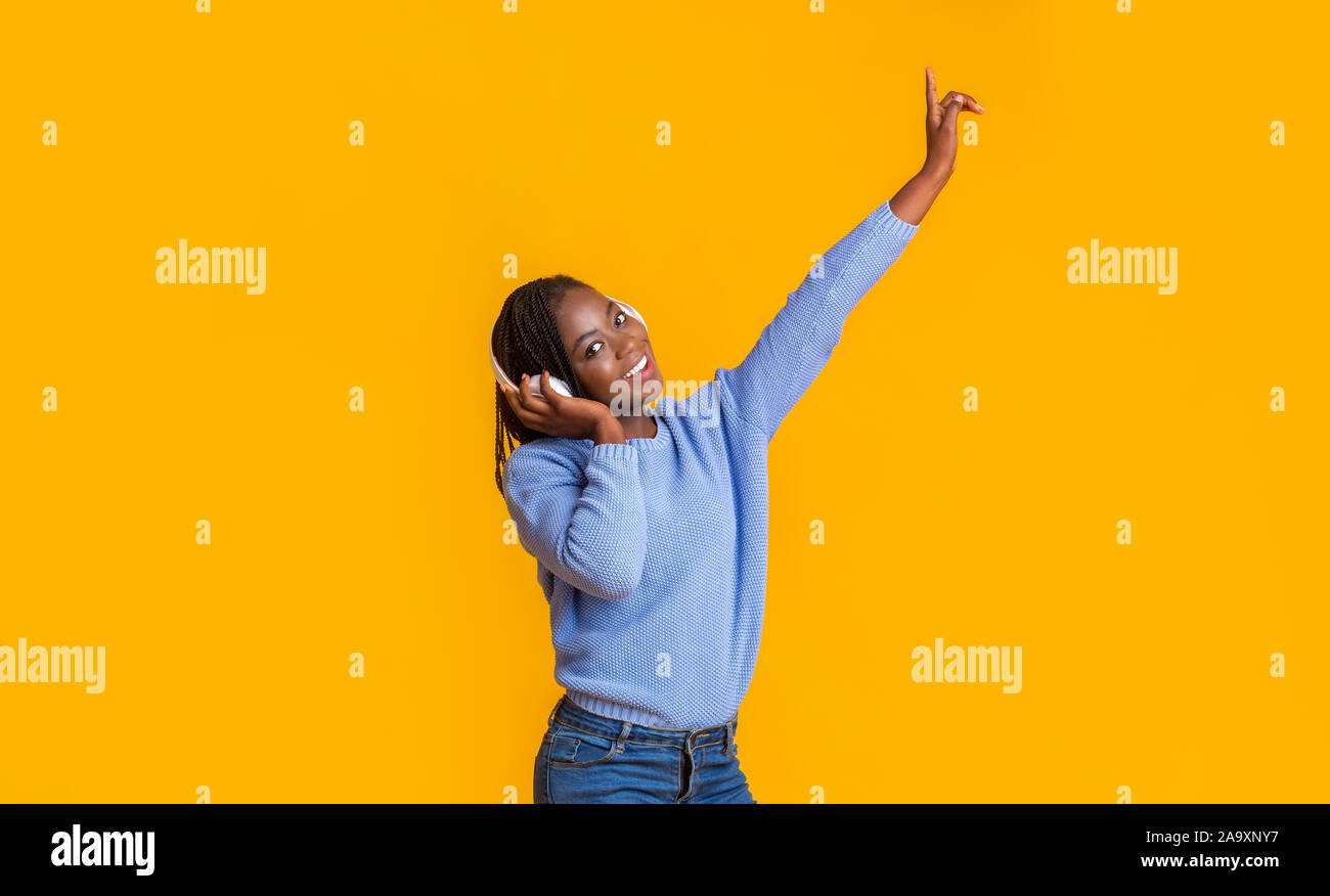 Verträumt afro Girl bei Musik, Tanzen auf gelbem Hintergrund Stockfoto
