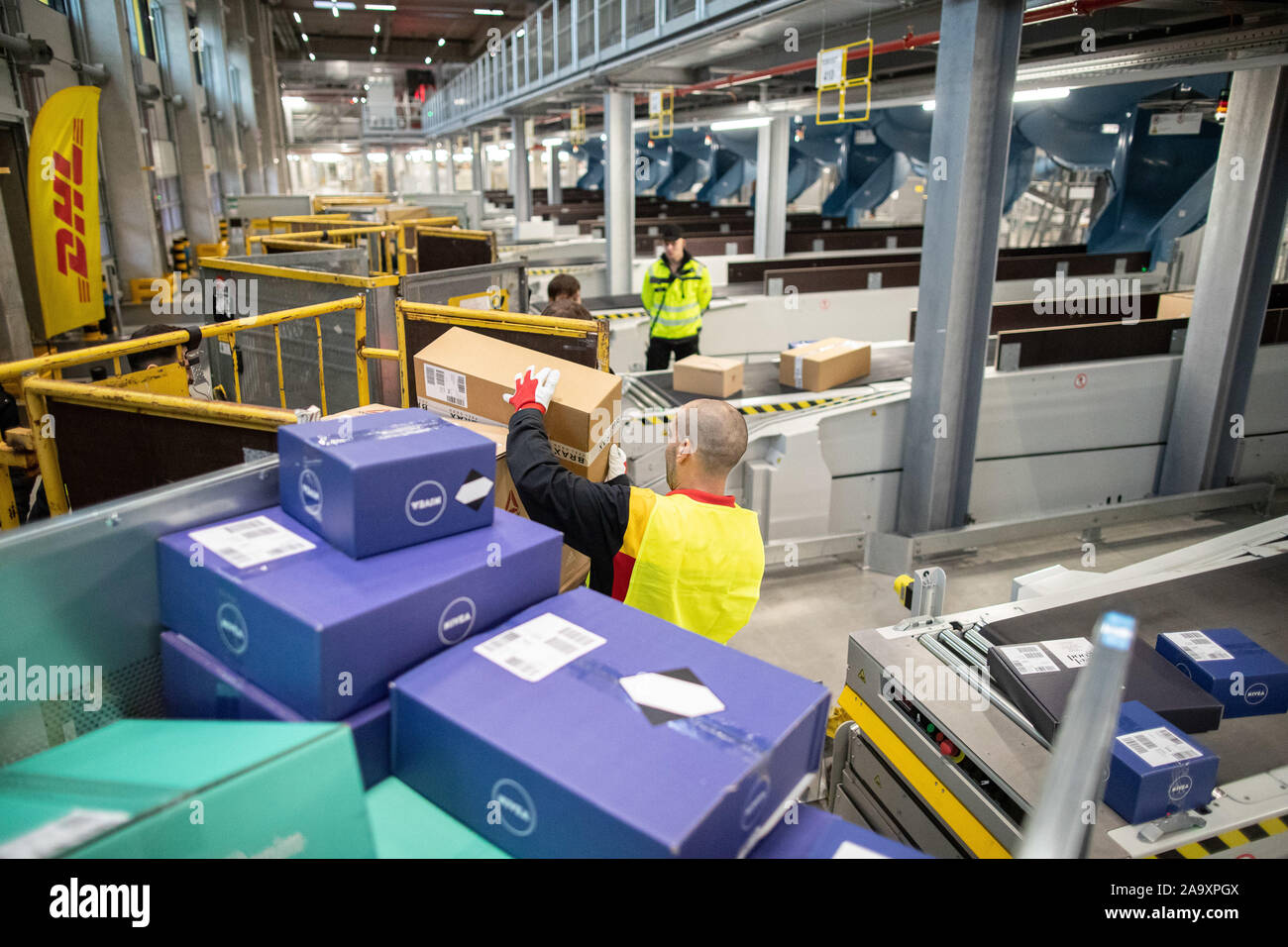 Bochum, Deutschland. Nov, 2019 18. Anlieferung Treiber Franko Orte ein Paket in einem Transportwagen. Deutsche Post DHL hat einen neuen Paketzentrum auf dem ehemaligen Opel Website eröffnet. Mit einer Sortierung Kapazität von bis zu 50.000 Sendungen pro Stunde in dem angestrebten Ziel, einer der effizientesten Paketzentren in Europa geht online in Bochum. Credit: Marcel Kusch/dpa/Alamy leben Nachrichten Stockfoto