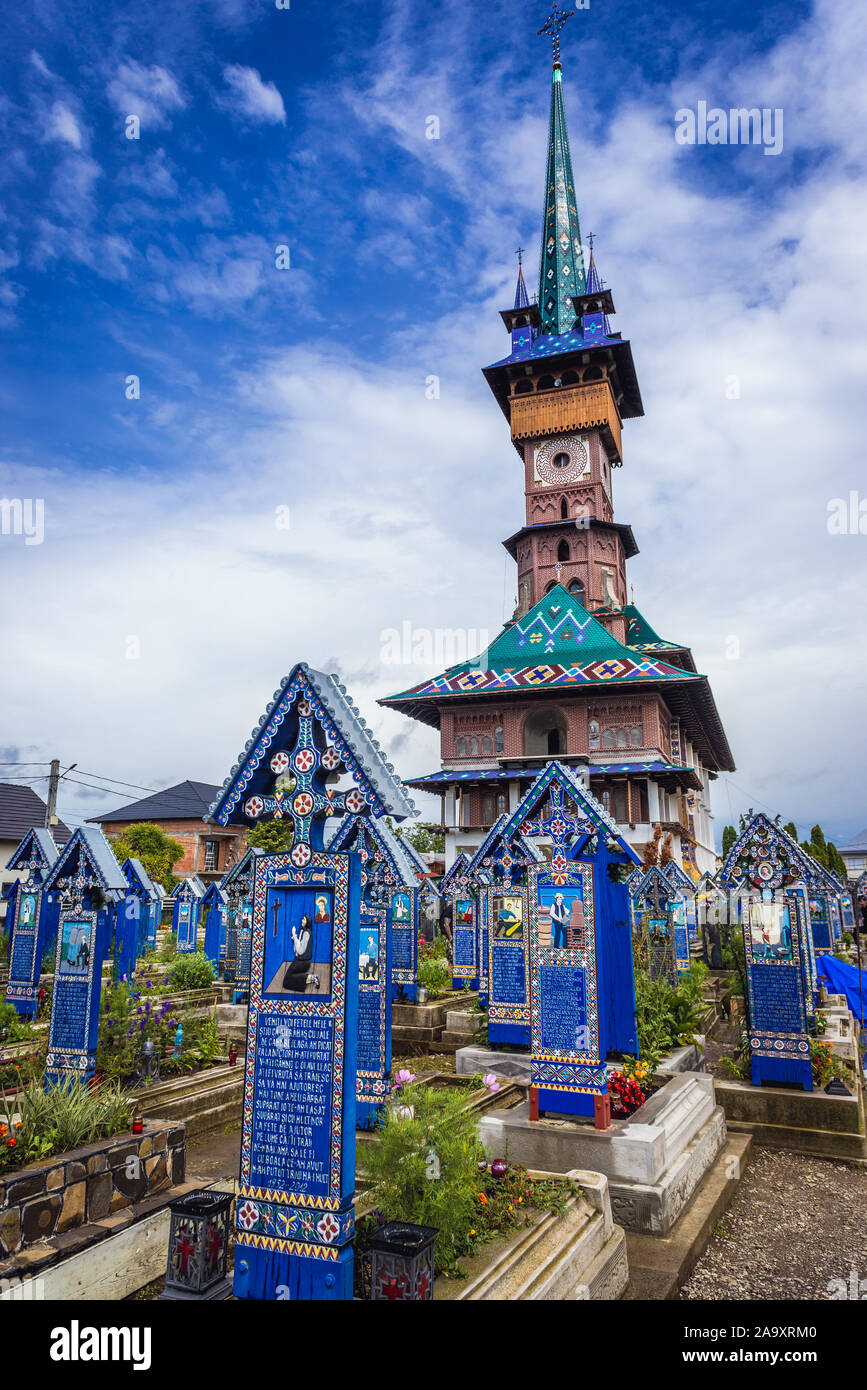 Gräber und die Geburt der Jungfrau Maria Kirche auf dem Friedhof Cimitirul Vesel - Frohe, berühmten Friedhof in Sapanta in Maramures, Rumänien Stockfoto