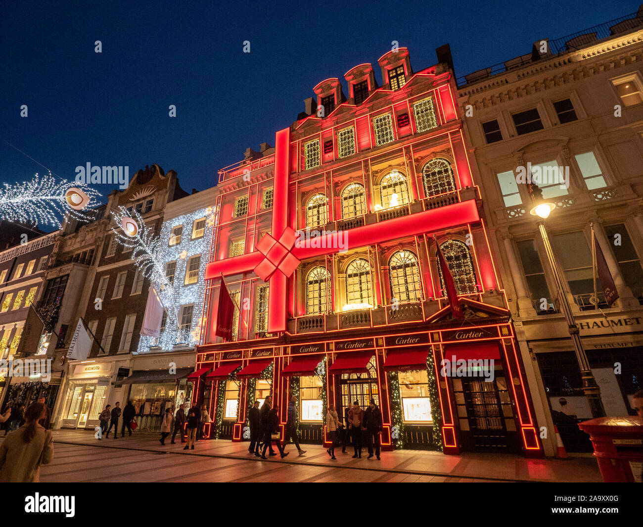 Festliche Lichter in der New Bond Street in der Nacht mit der roten Fassade von Cartier, Mayfair, London. Stockfoto