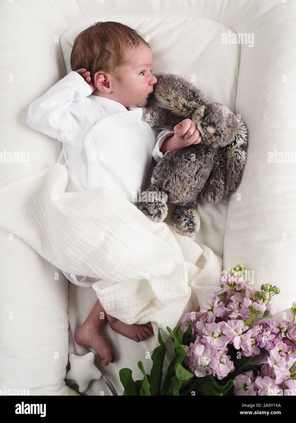 Neugeborenes Baby Boy liegend auf Bett und Schlafen mit Teddybär. Ihr Baby braucht seinen Schlaf. Blumenschmuck der kinder Bett Stockfoto