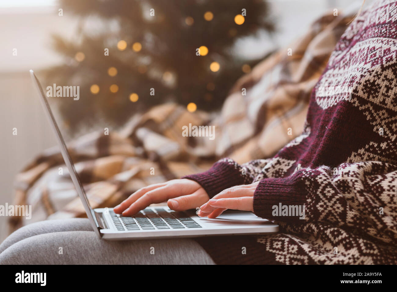 Frau in warmen Pullover mit Laptop über Weihnachten Dekoration Zimmer Stockfoto