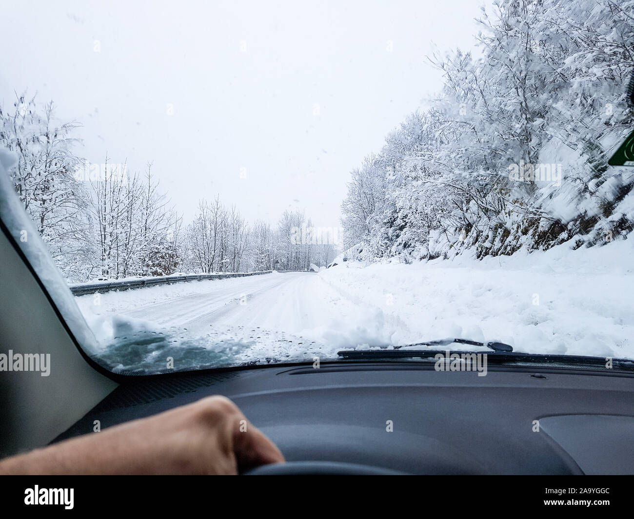 Das Fahren auf schneebedeckten Straßen bei Schneefall. Straße im Winter von innen im Auto gesehen. Schwierige Bedingungen. Stockfoto