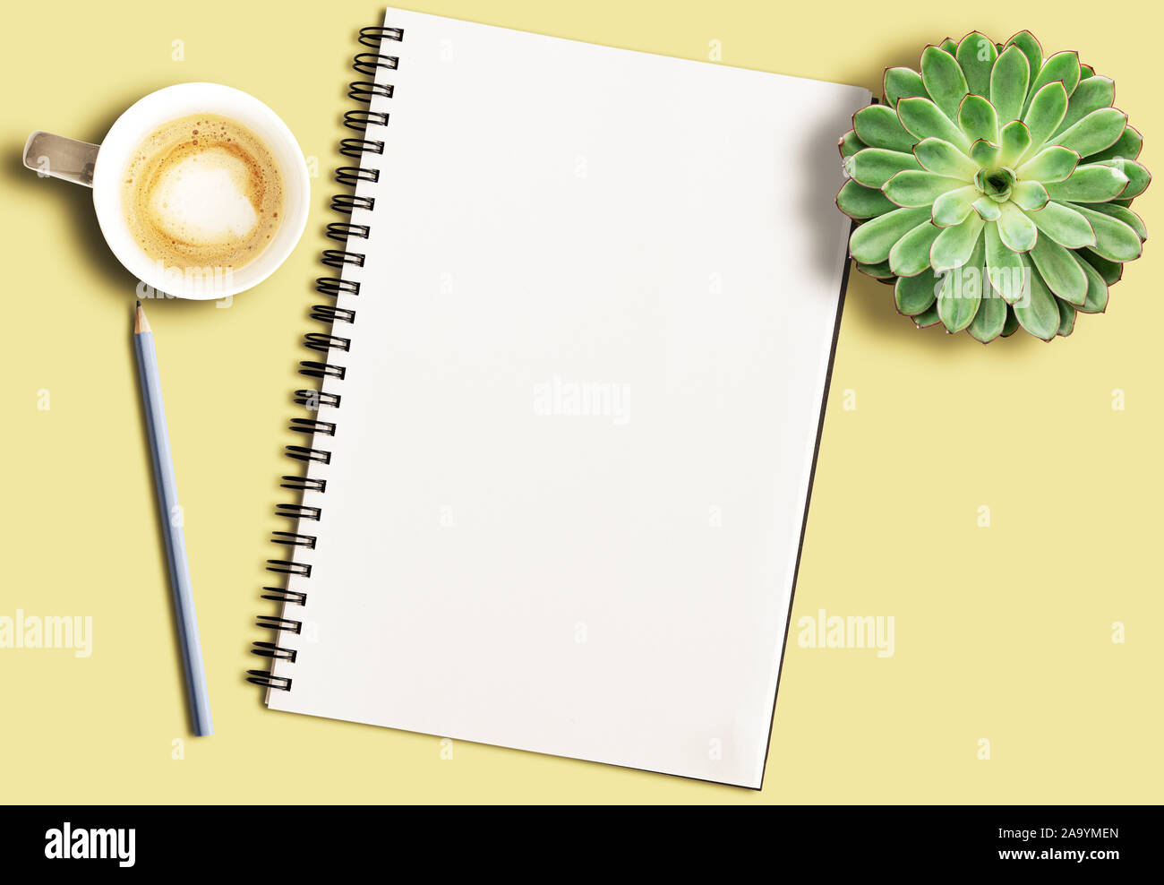 Leere Spirale Notizblock auf gelb Schreibtisch mit Bleistift, Topfpflanzen sukkulente Pflanze und Coffee Mug Stockfoto