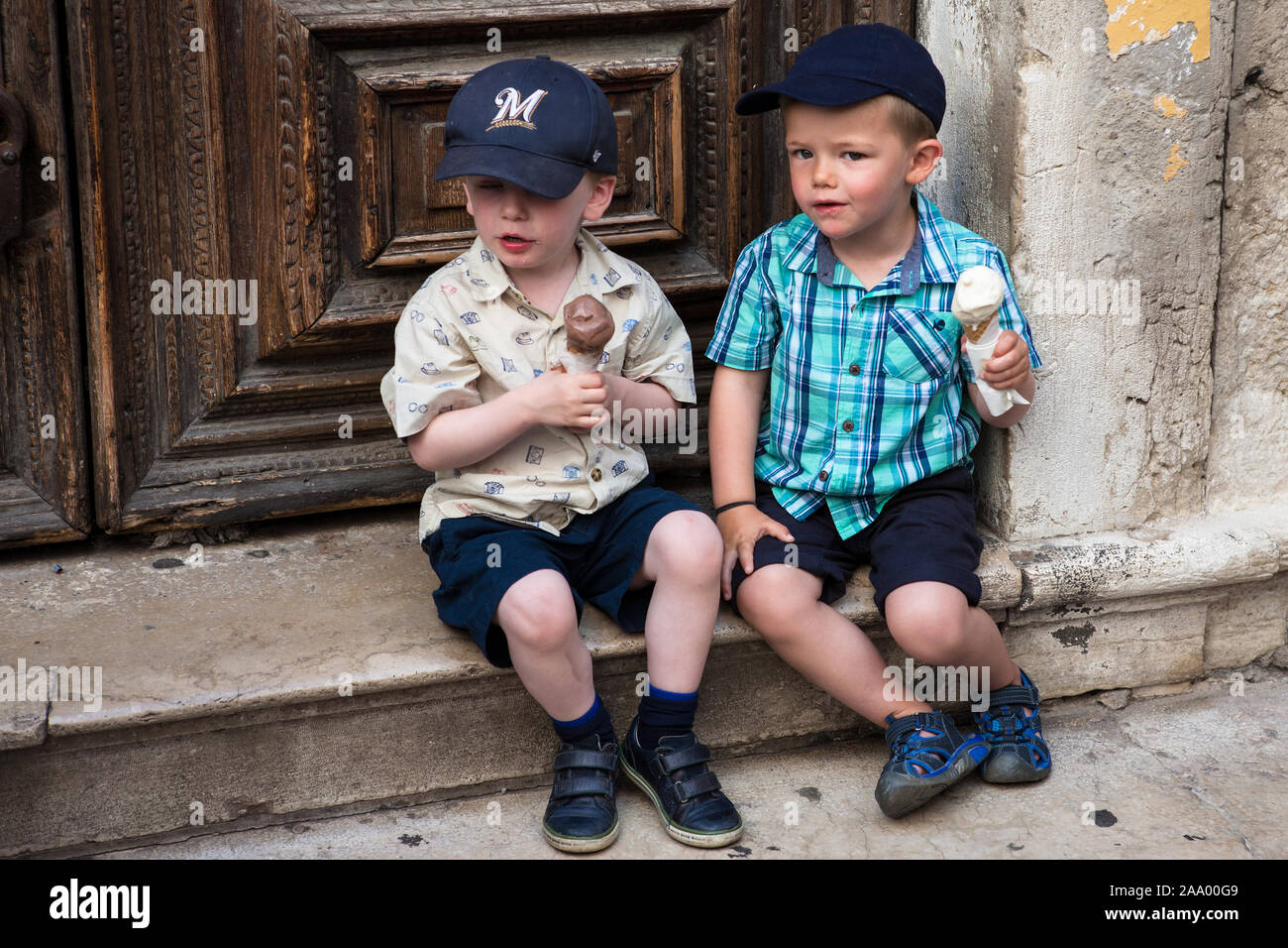 Zwei kleine Jungs sitzen auf einer Stufe mit ihren Eis, Salizzada Pio X, San Marco, Venedig, Italien Stockfoto
