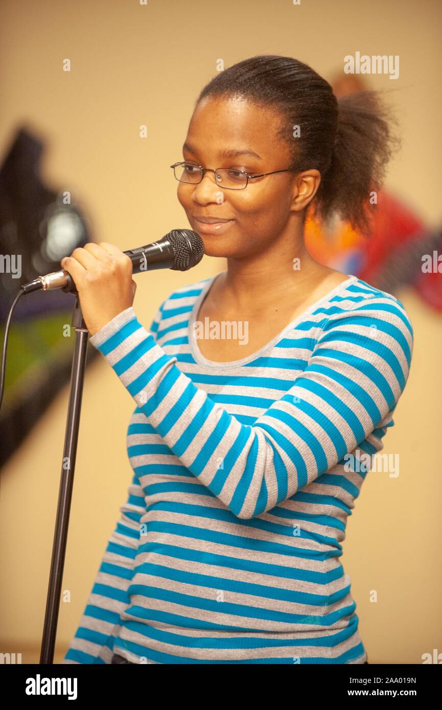 Drei Viertel Profil ansehen, von der Taille, mit einem lächelnden Person fassen Sie den Griff eines montierten Mikrofon während eines Black History Month Poetry Slam Veranstaltung an der Johns Hopkins Universität, Baltimore, Maryland, 7. Februar 2009. Vom Homewood Sammlung Fotografie. () Stockfoto