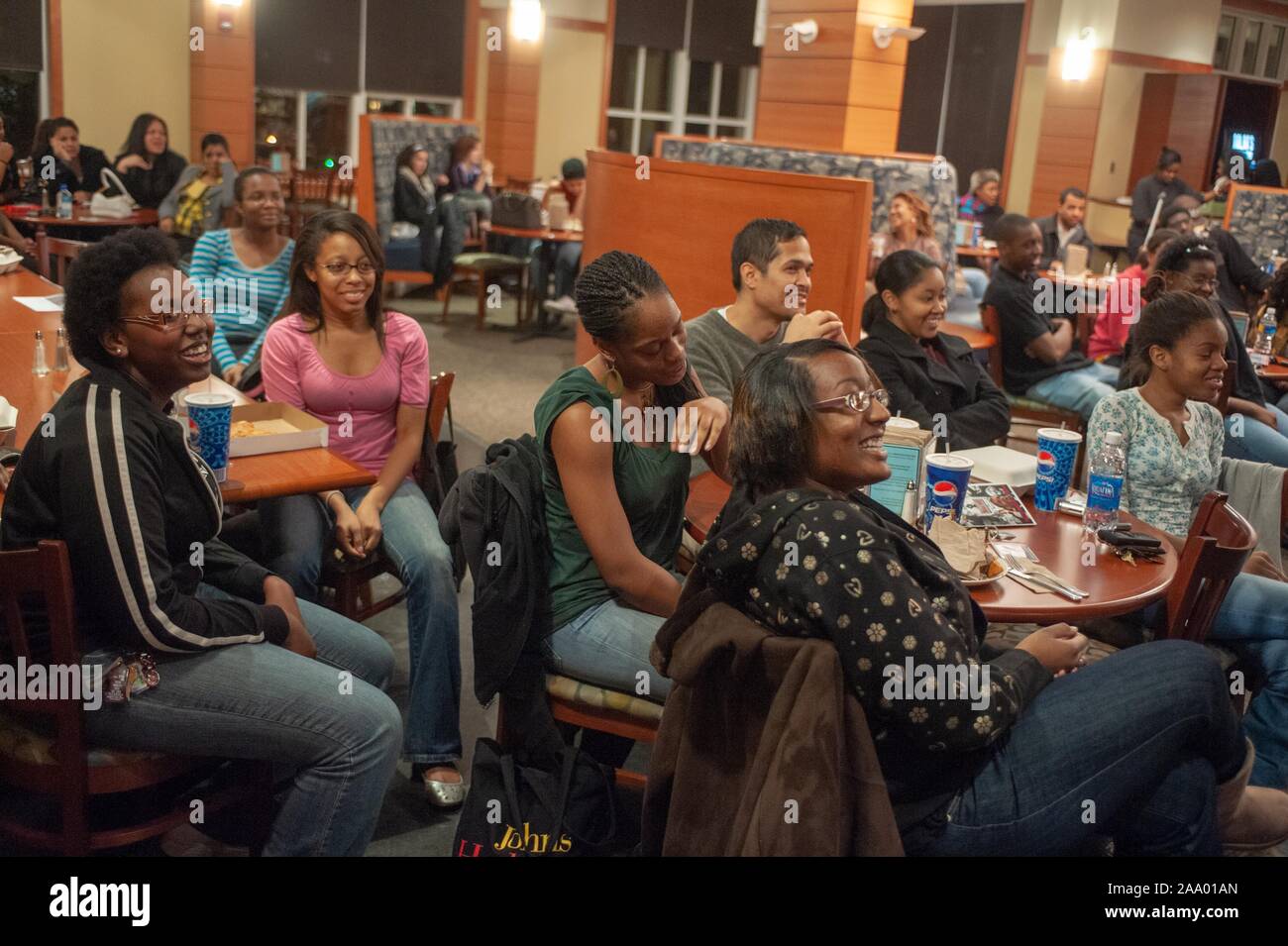 Mitte der Schuß von lächelnden Menschen an Tischen sitzen, Zuzusehen - Aktion der Kamera, während des Black History Month Poetry Slam Veranstaltung an der Johns Hopkins Universität, Baltimore, Maryland, 7. Februar 2009. Vom Homewood Sammlung Fotografie. () Stockfoto
