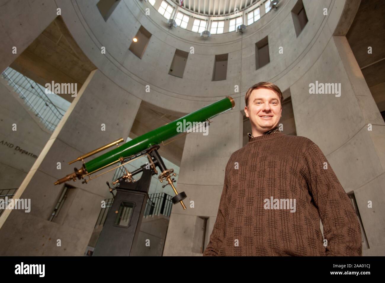 Froschperspektive von David Thilker, Principal Research Scientist in der Henry einen Rowland Fakultät für Physik und Astronomie, stehend in einer Sternwarte neben einem Teleskop und lächelnd in die Kamera, an der Johns Hopkins Universität, Baltimore, Maryland, 13. Februar 2009. Vom Homewood Sammlung Fotografie. () Stockfoto