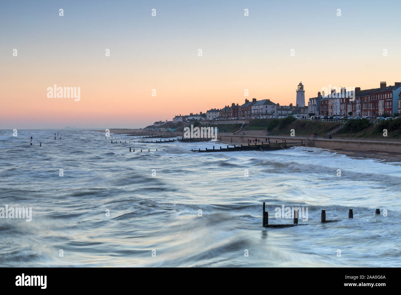 Wellen brechen am Southwold Beach mit Blick auf die Stadt und den Leuchtturm auf dem Hügel, Suffolk, Großbritannien Stockfoto