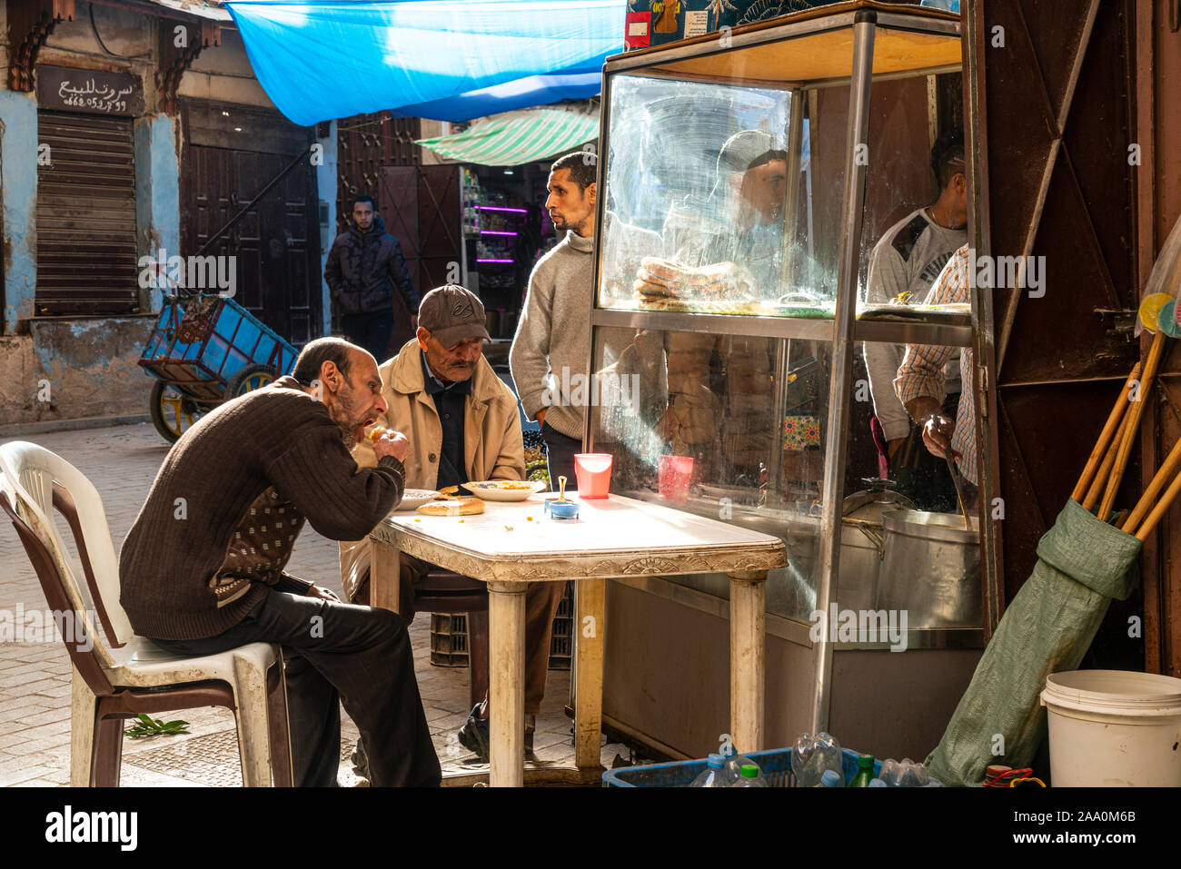 Fez, Marokko. November 9, 2019. Zwei Männer essen auf einem Tisch auf der Straße Stockfoto