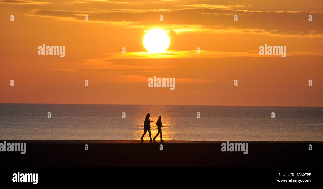 Männliche und weibliche Paar in Silhouette gegen den roten Sonnenuntergang Stockfoto