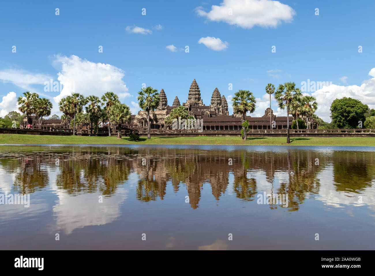 Angkor Wat und seine Reflexion in den See. Der blaue Himmel ist mit einem flauschigen weissen Wolken zerstreut. Alles ist frisch und grün im regnerischen seaso Stockfoto