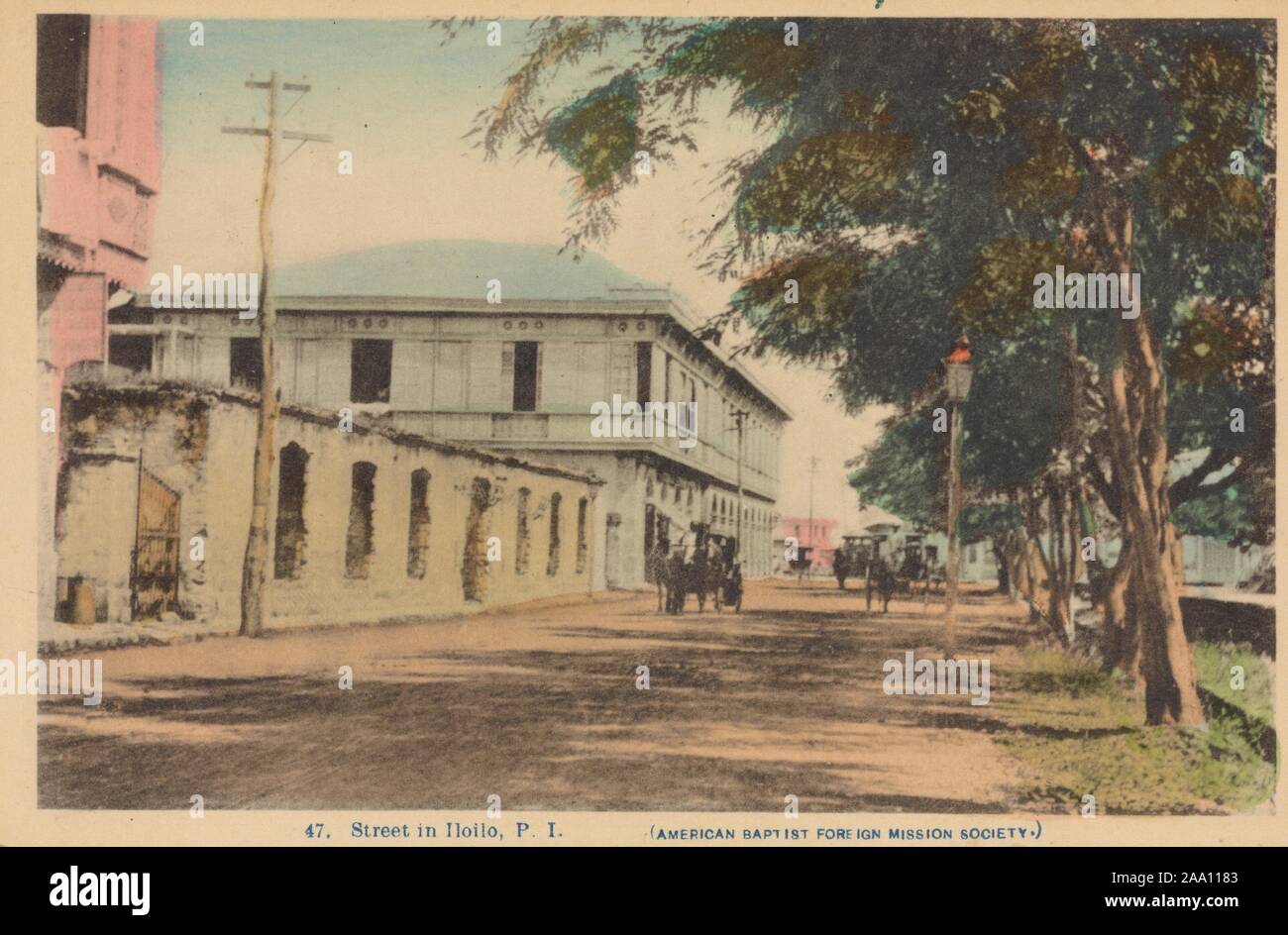 Illustrierte Foto von einer Straße mit Gebäuden auf der einen Seite und einer Reihe von Bäumen auf der anderen, in Iloilo, Panay Island, Philippinen, von der American Baptist Foreign Mission Society, 1910 veröffentlicht. Von der New York Public Library. () Stockfoto