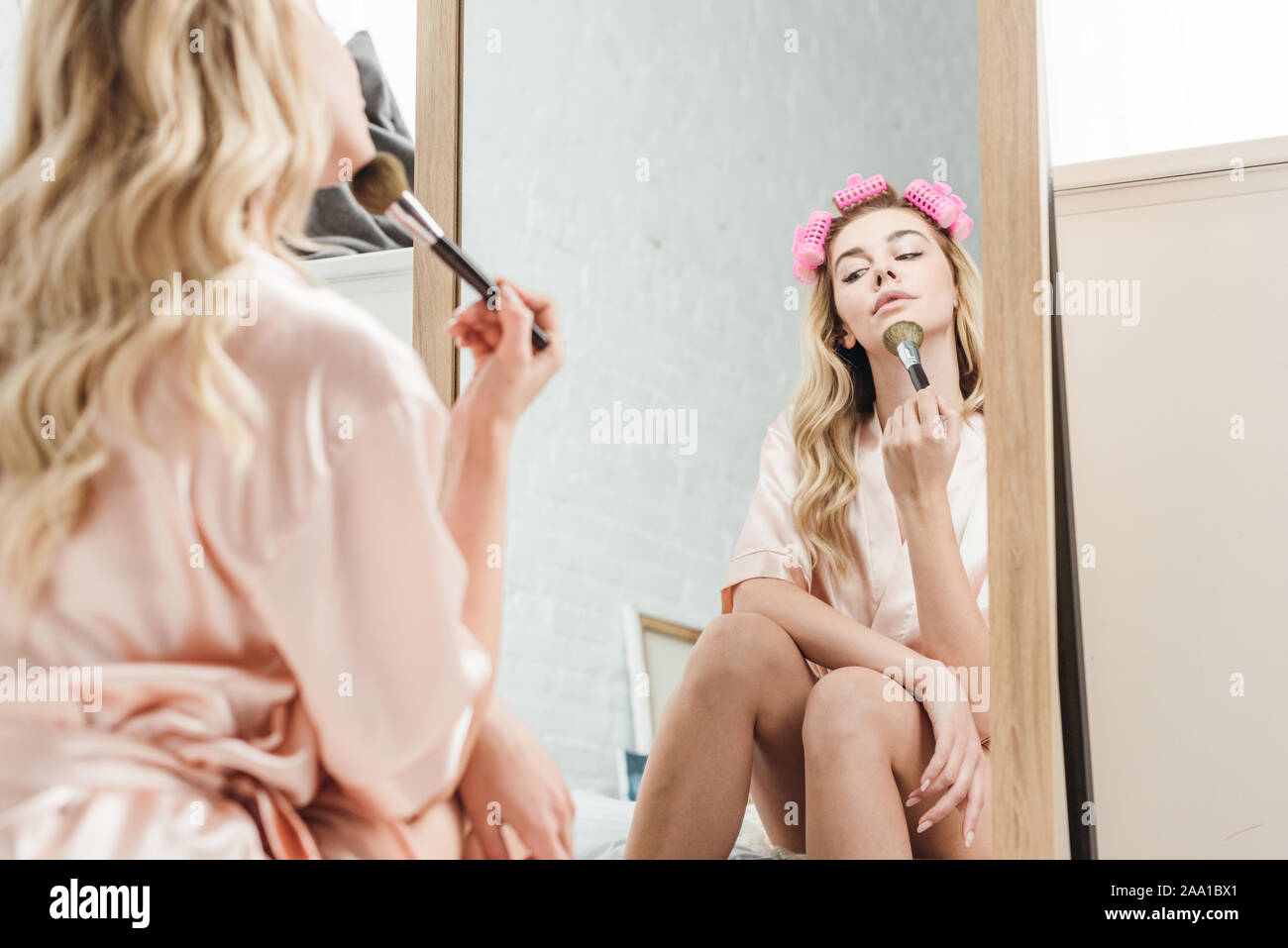 Selektiver Fokus der schönen Mädchen mit Lockenstäbe Holding kosmetische Bürste und Spiegel Stockfoto