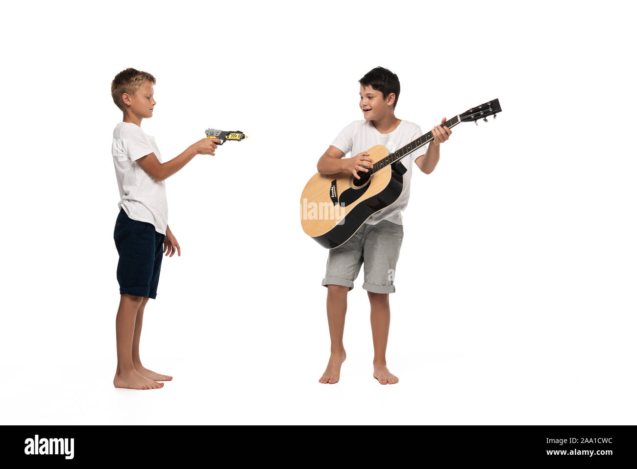 Zwei Brüder auf der Suche an Kamera und Tanz beim Hören von Musik über Kopfhörer auf weißem Hintergrund Stockfoto