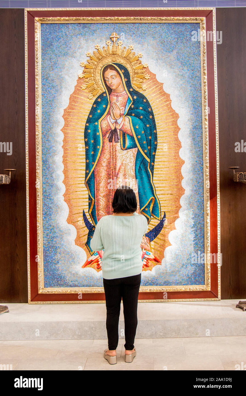 Ein Hispanic Anbeter bewundert ein Porträt unserer Lieben Frau von Guadalupe, die von Künstler Valerio Lenarduzzi an eine Kathedrale in Orange, CA. Die Jungfrau von Guadalupe (Spanisch: Virgen de Guadalupe), ist eine Katholische Titel der Allerseligsten Jungfrau Maria mit einer Marienerscheinung verbunden. Stockfoto