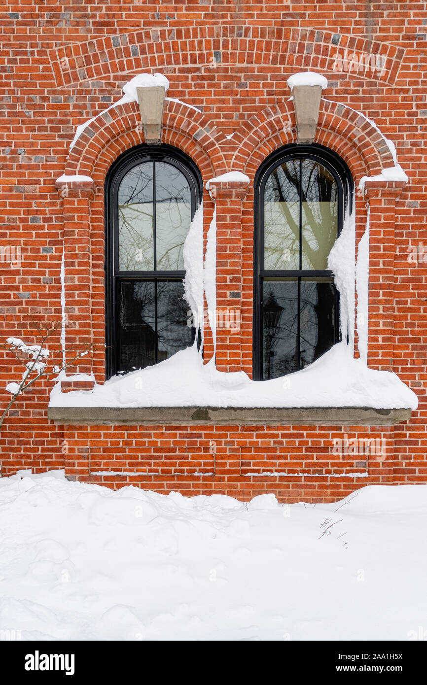 Der Schnee türmt sich in Windows ein älteres Backsteingebäude. Stockfoto
