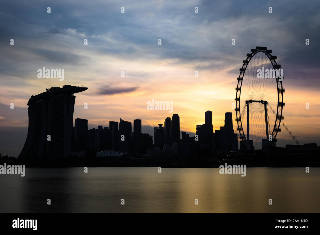 Atemberaubender Blick auf die Silhouette der Marina Bay Skyline mit Wolkenkratzern und ein Riesenrad bei einem atemberaubenden Sonnenuntergang in Singapur. Stockfoto