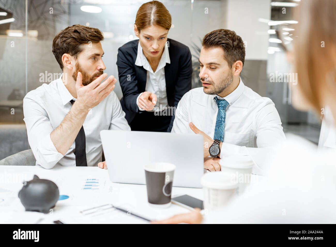 Team Leader helfen zwei männliche erschöpft, Mitarbeiter der Arbeit auf einem Laptop im Büro zu tun Stockfoto