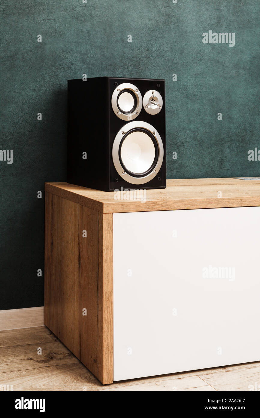 Eine moderne schwarz Audio Lautsprecher System im Innenbereich auf Holz Schreibtisch in der Nähe des dunklen grünen Wand. Bild vertikal Stockfoto