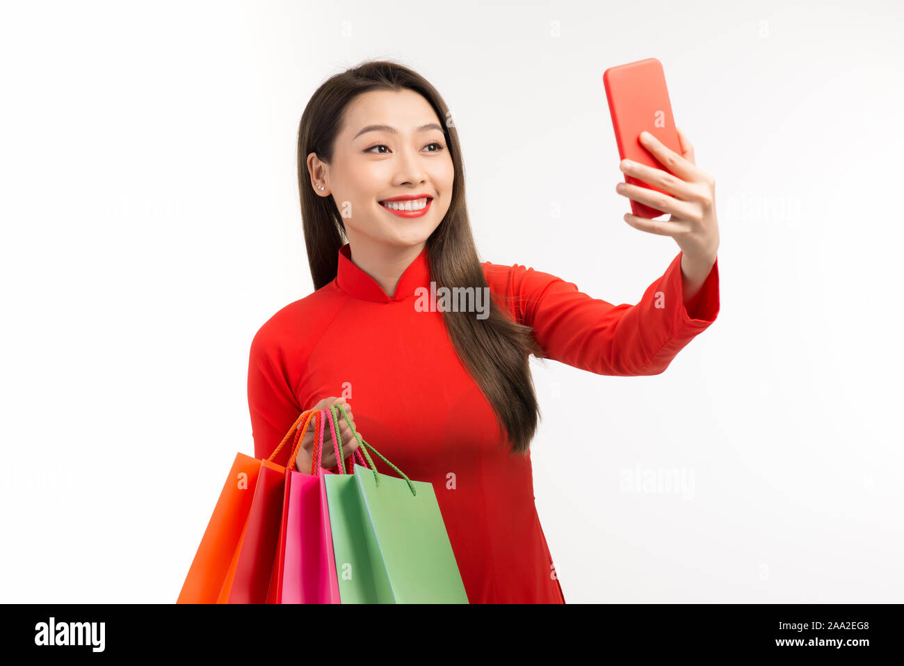Shopping am Neujahrsfest, schöne Frau mit Taschen und selfie, Kleid in rot Tracht für die Vietnamesische Bevölkerung. Stockfoto
