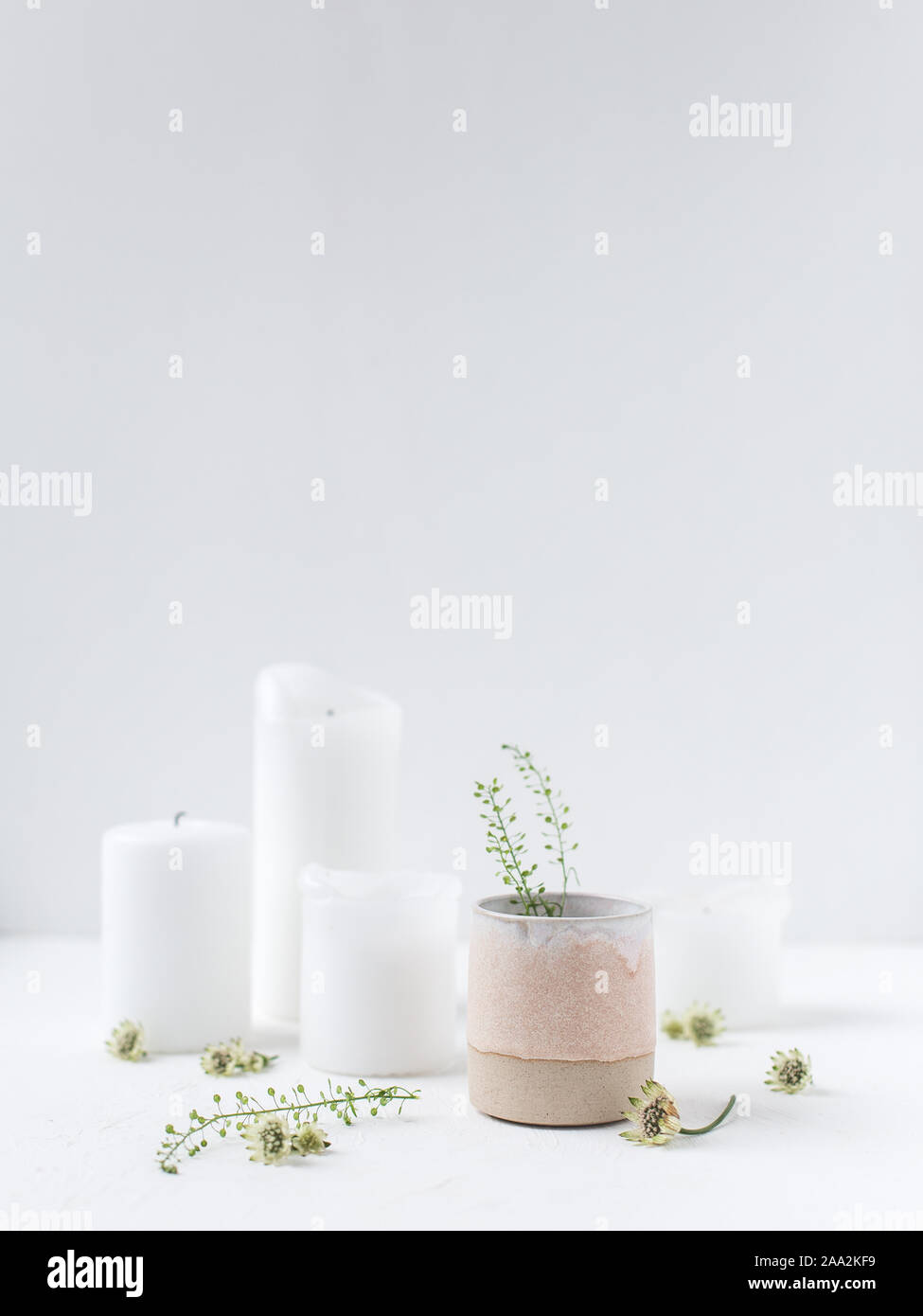 Kerzen und Blumen in einer Vase aus Keramik Stockfoto