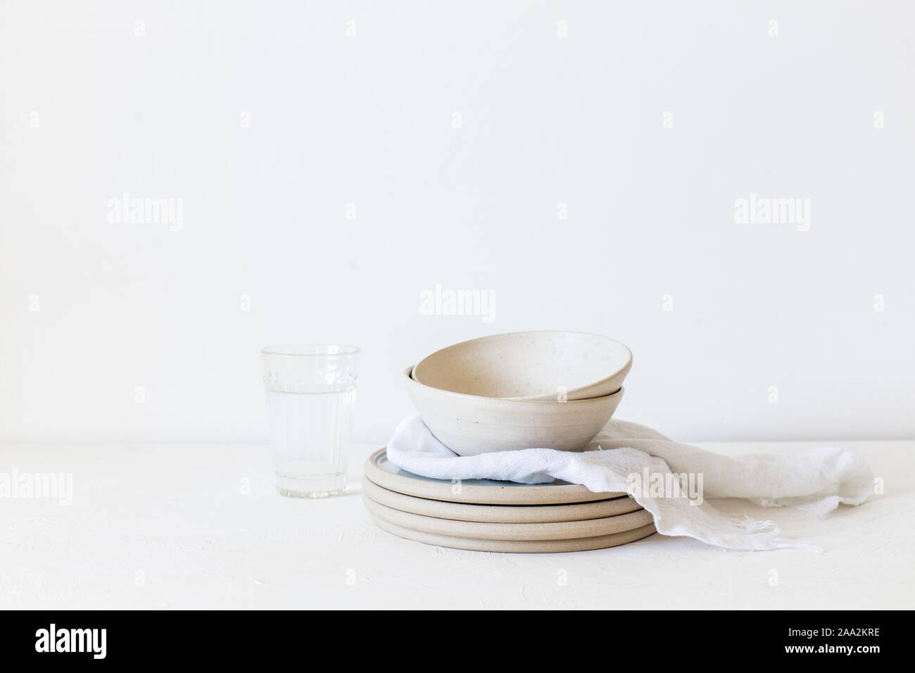 Stapel von keramischen Platten und Schüsseln neben einem Glas Wasser Stockfoto